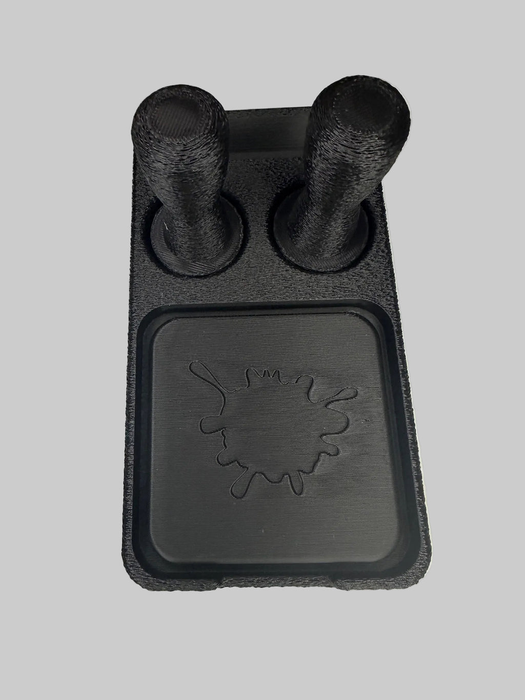 Black 3D-printed object with cylindrical protrusions on a white surface