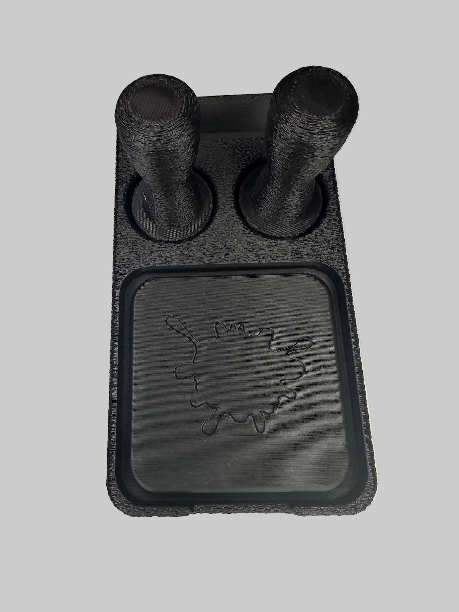 Black 3D-printed object with cylindrical protrusions on a white surface