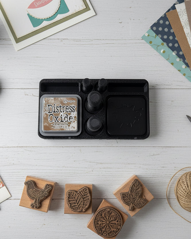 Distress Oxide ink pad with a black ink pad holder on a white surface
