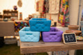 Three colorful pillow baskets stacked on a wooden table
