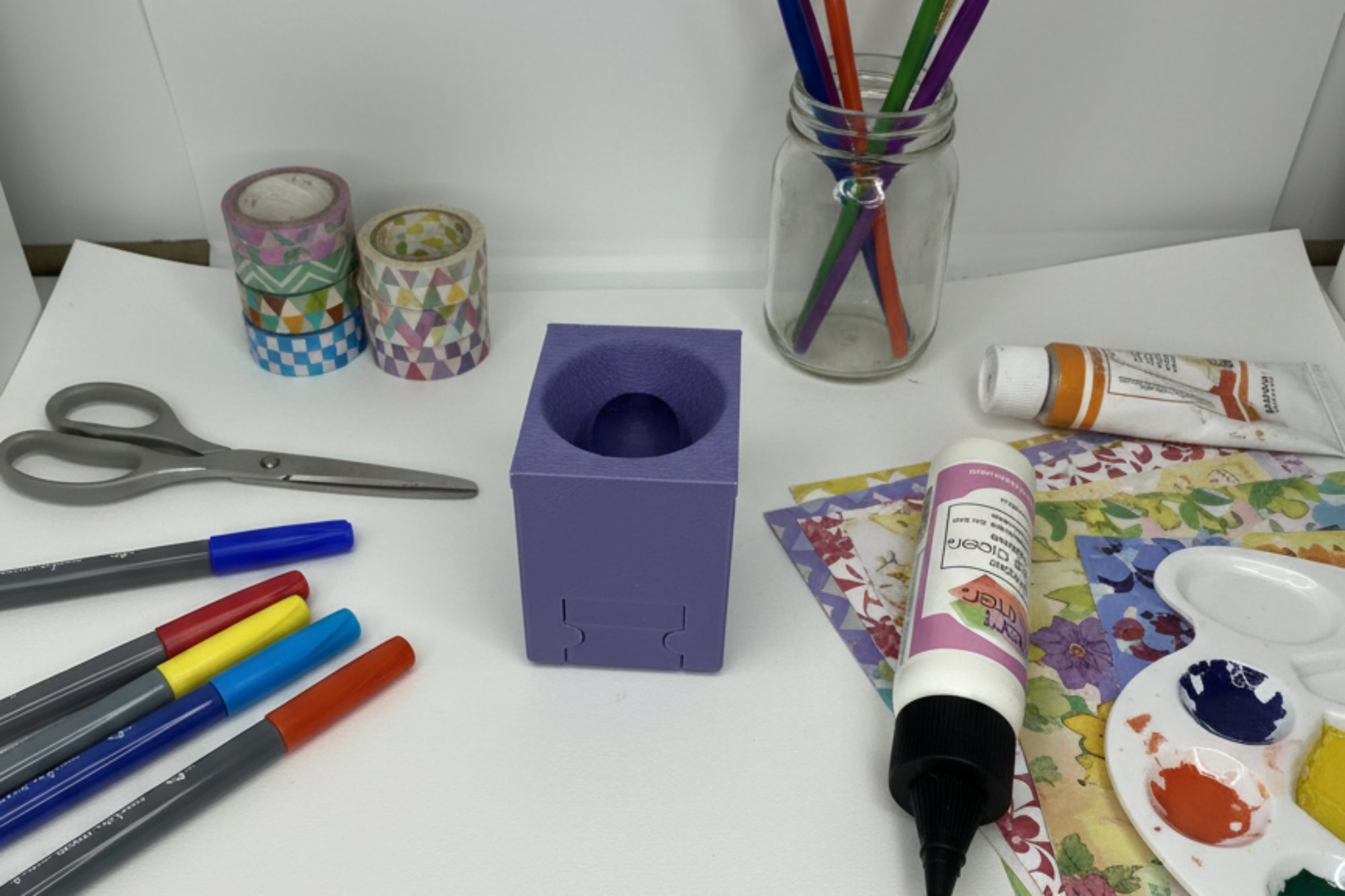 Purple square object with a circular indentation next to a bottle of glue on a white background