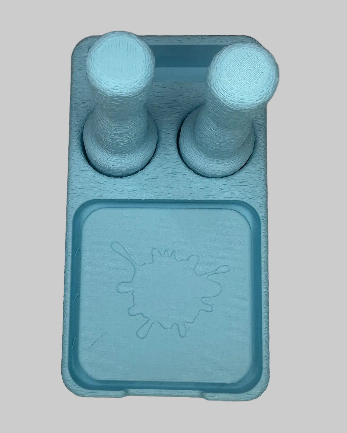 Blue ice cube tray with two cylindrical molds on a white surface