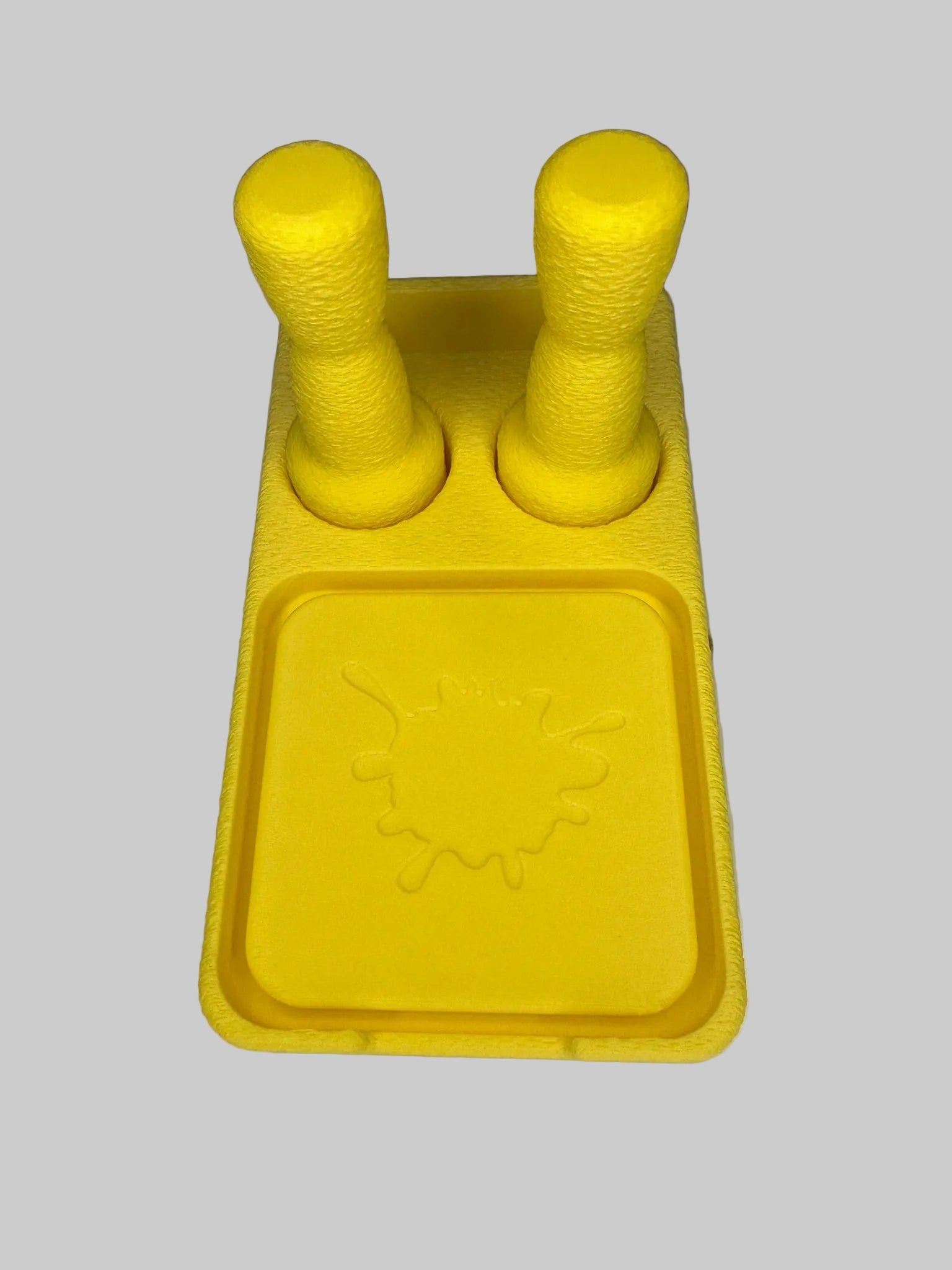 Yellow plastic tool with two cylindrical handles on a white surface